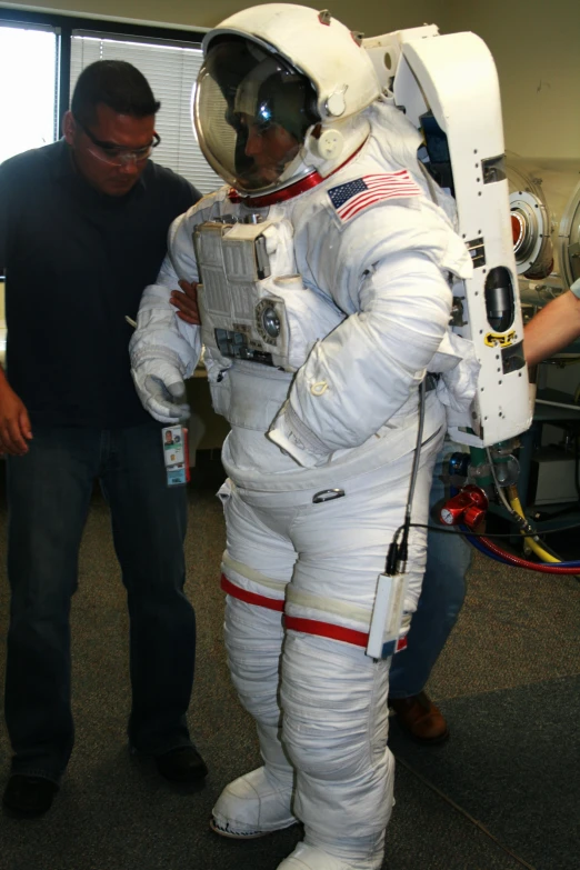 two men dressed in spacesuits and helmets, standing next to each other