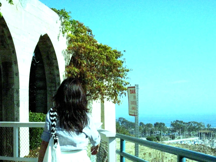 a woman standing on the balcony looking at the ocean