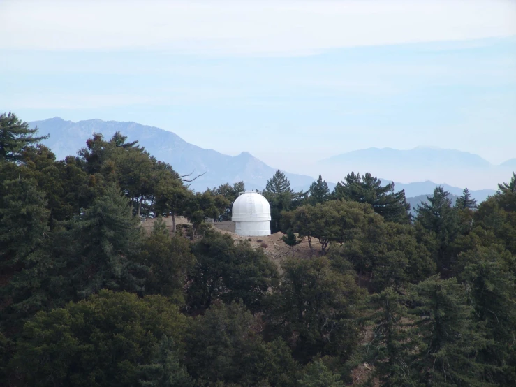 a small white building is sitting among some trees