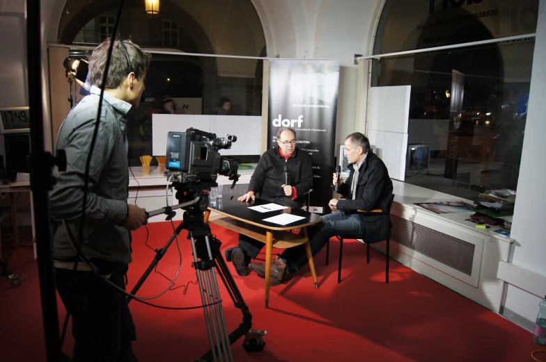 two people in a studio talking and sitting around a table