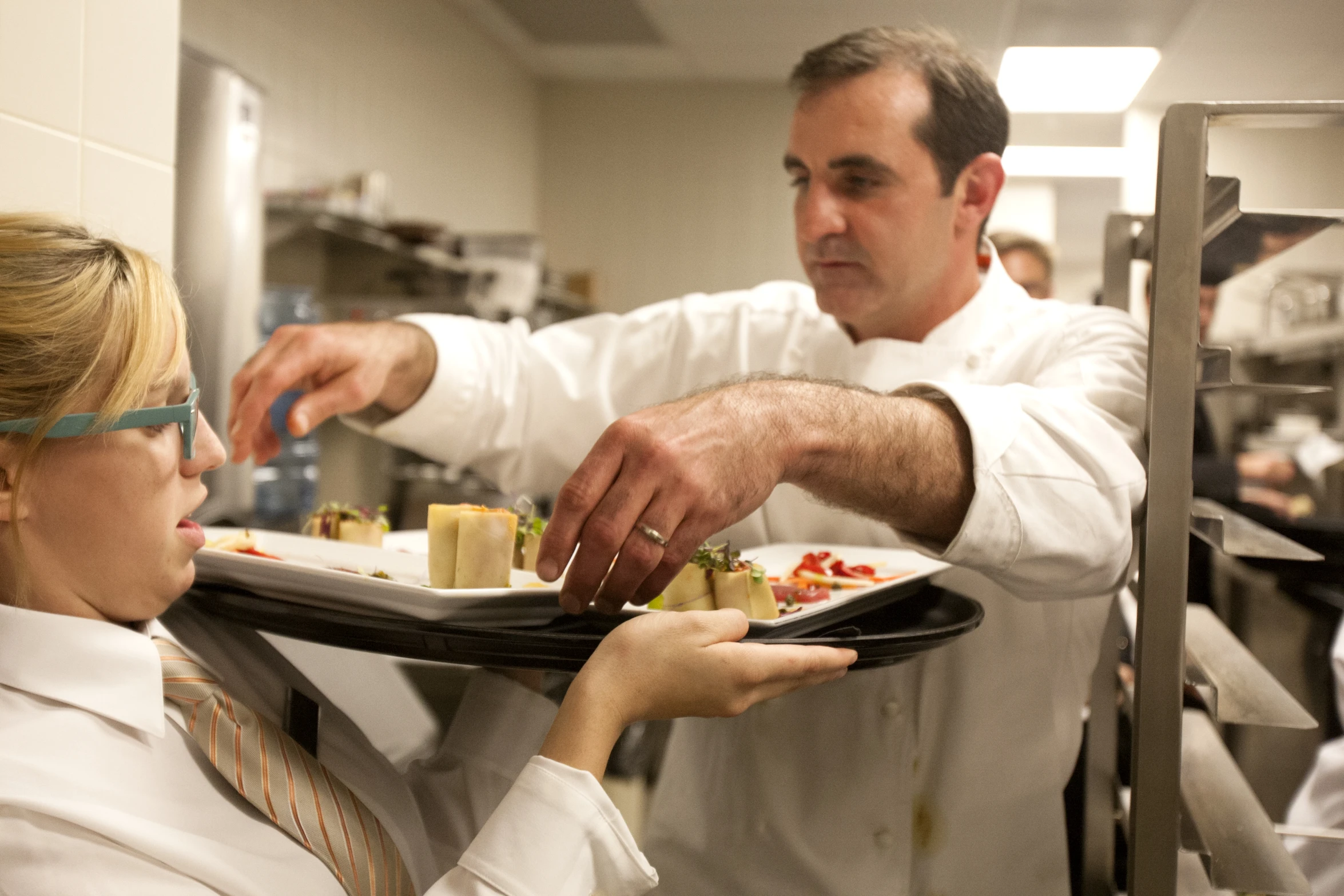 a chef is putting a plate of food on to a woman