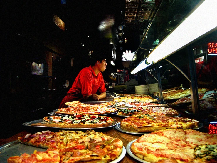 a man is selecting and buying a variety of pizzas in a store