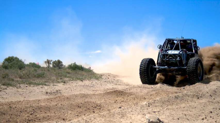 the four wheeled vehicle is going down the dirt road