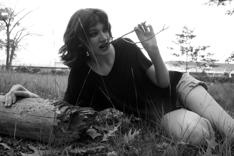 the girl is sitting in a field and holding a stick