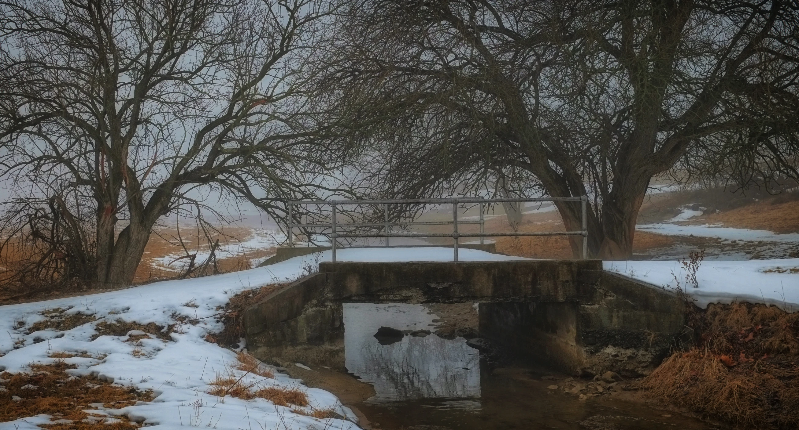 a small bridge on top of a snowy hill