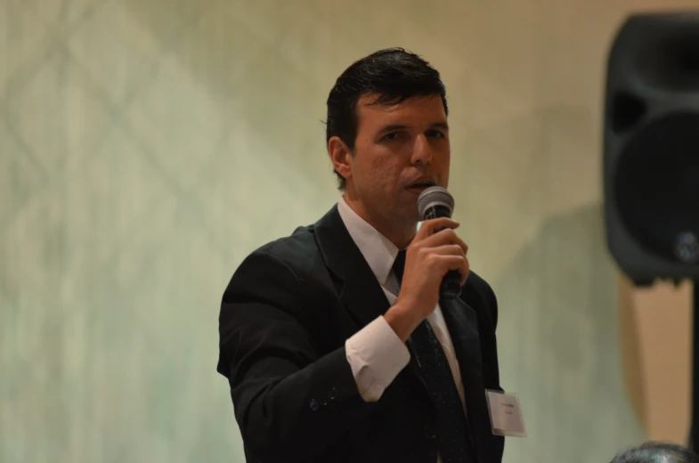 a man talking into a microphone in a suit