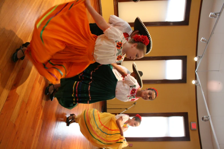 three people in mexican dress dancing on a wooden floor