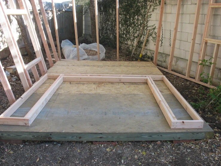 wood framing with unfinished boards around it, with plants in background