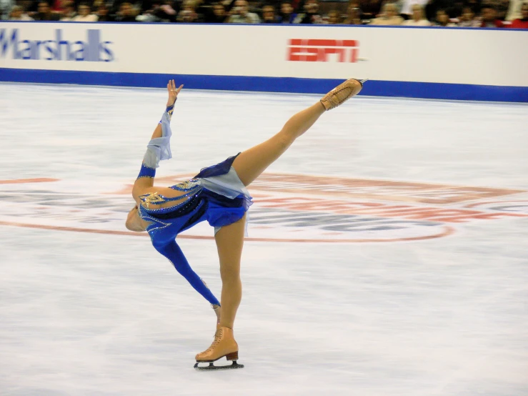 a female figure is performing on ice in an arena