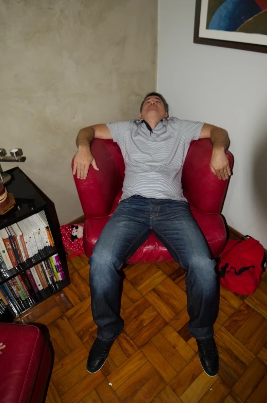 a man laying in a red chair with his arms crossed