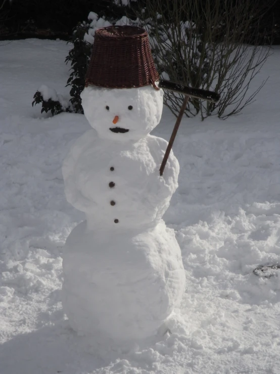 a snow man holding a hat and digging a hole in the snow