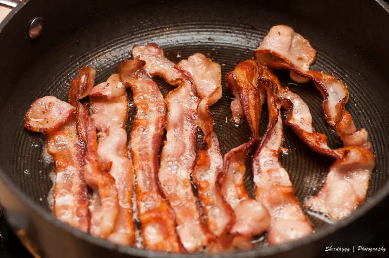 bacon is being cooked in a pan on the stove