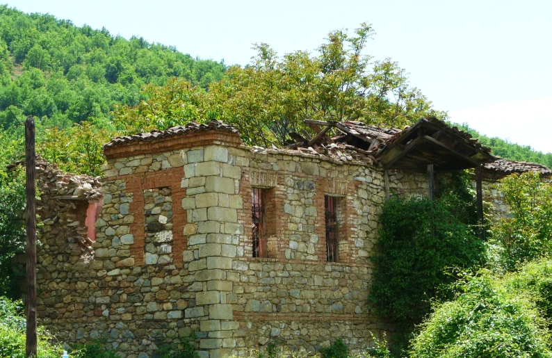 a small old brick building surrounded by trees