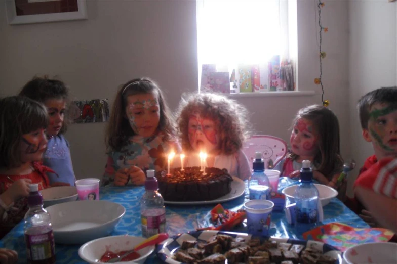 a group of children at a birthday party blowing out candles on cake