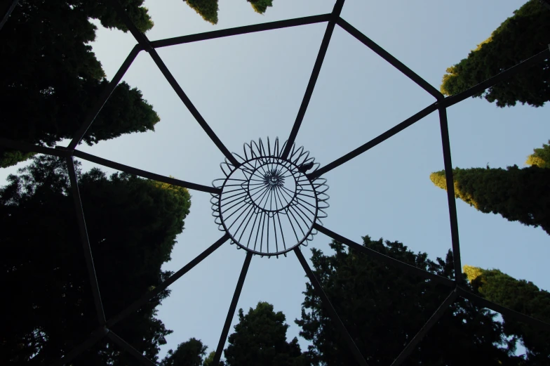 a metal structure sitting between trees and a blue sky