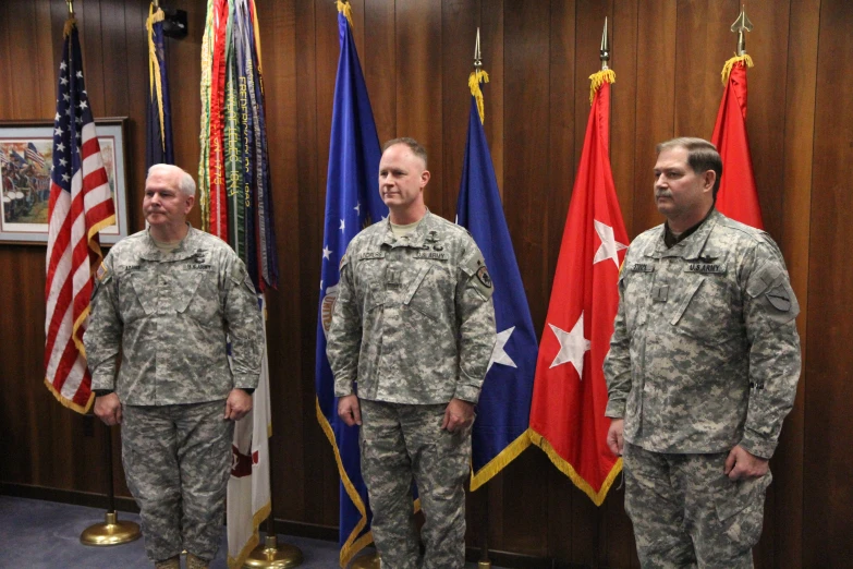 three soldiers standing in front of flags in the courtroom