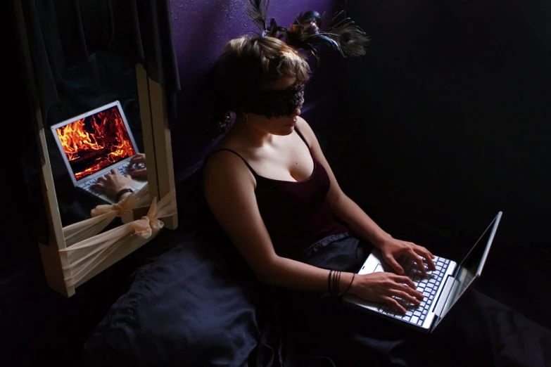 a girl wearing black dress sitting down on her laptop