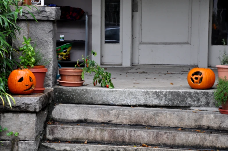 three carved pumpkins sitting on the step of an old house