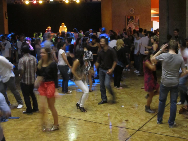people dancing and talking in a large room with lights
