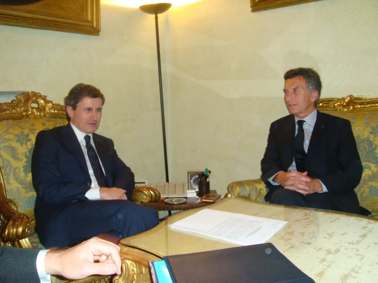 two men are sitting at a table talking