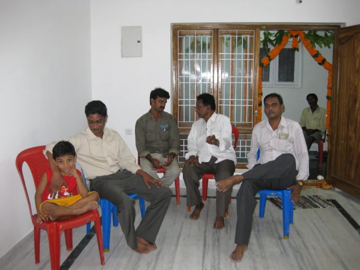 four people sitting down with one small child