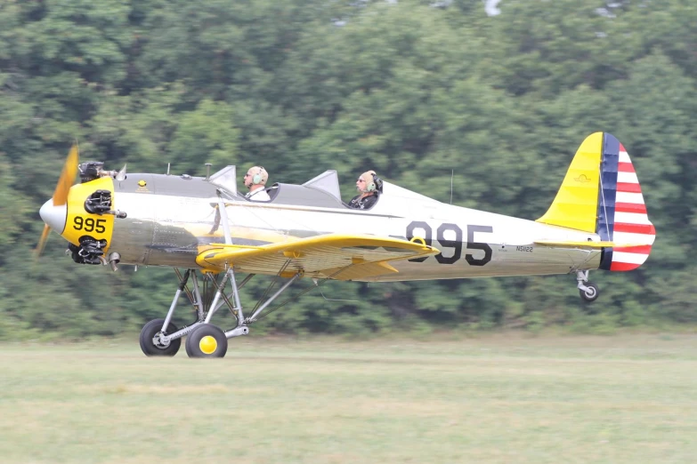 a yellow and gray airplane flying low over the ground