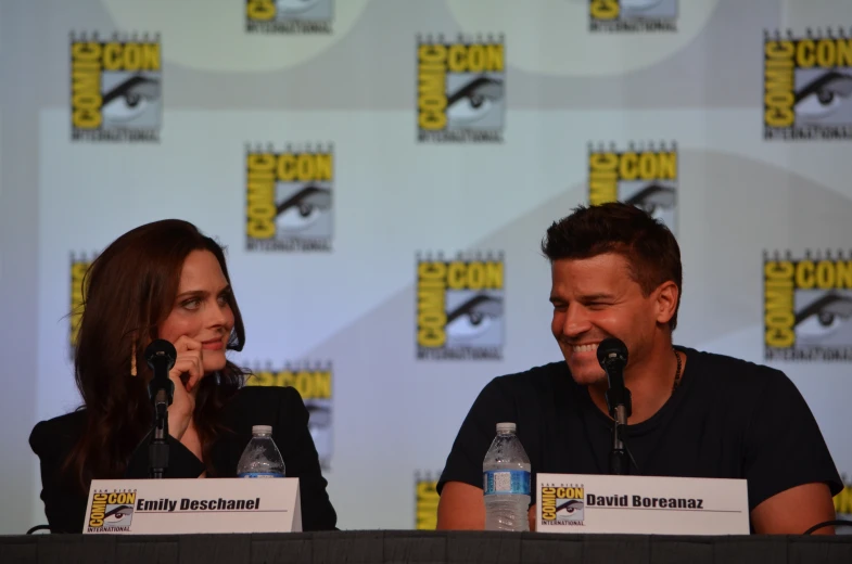 two actors smiling while having a conversation on stage