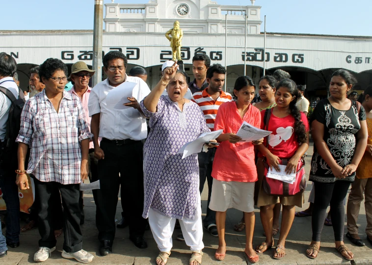 a group of people stand outside with a large clock in the background