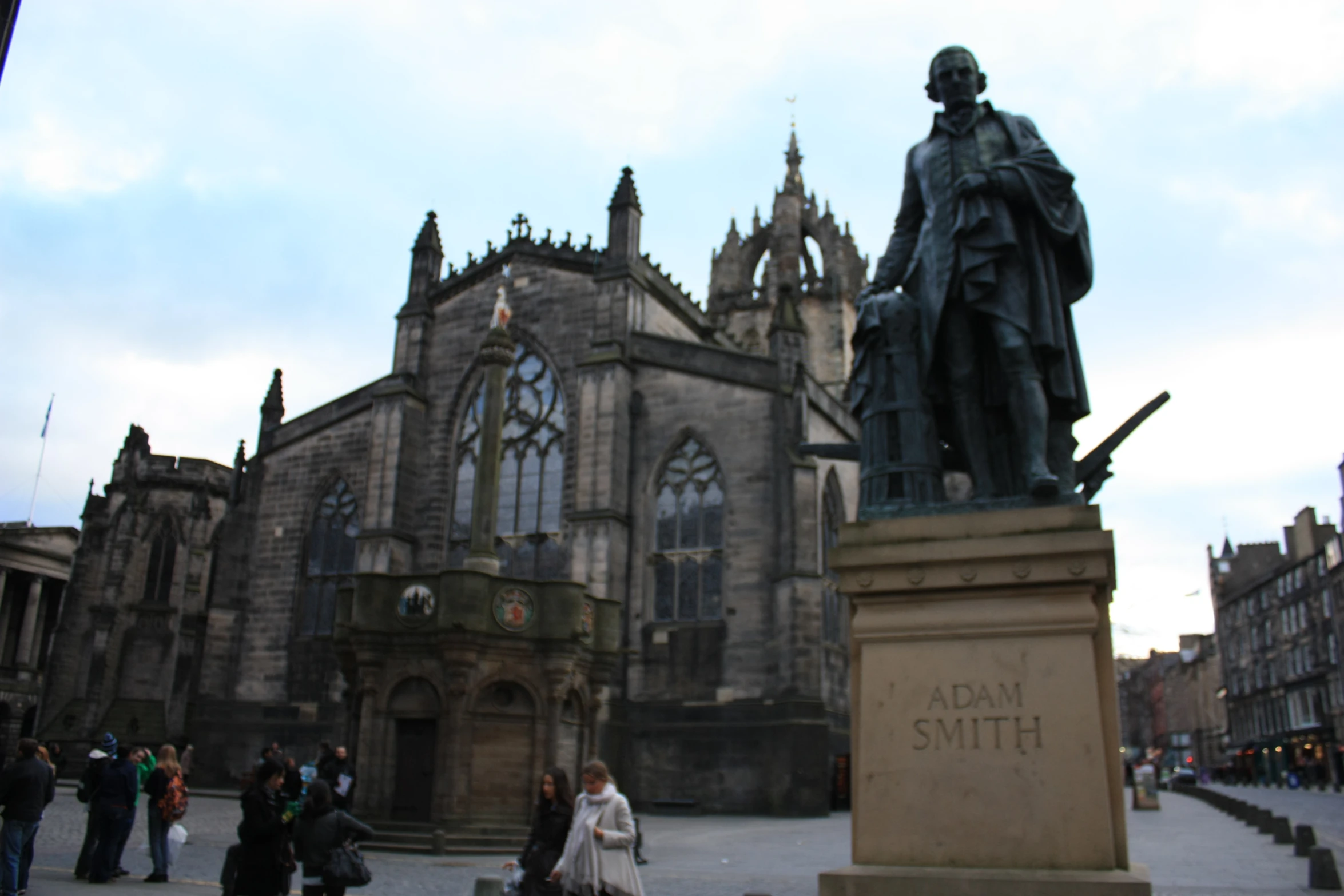 a statue in front of an old building with people standing around