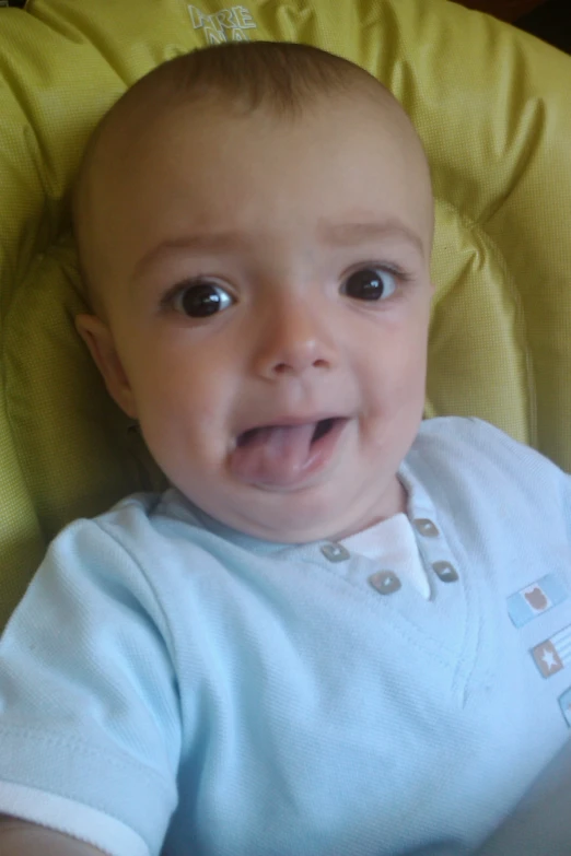 a baby with a smiling face sitting in a chair