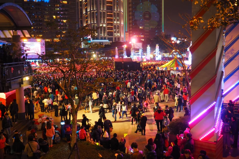 an outdoor event with many people and lit lights