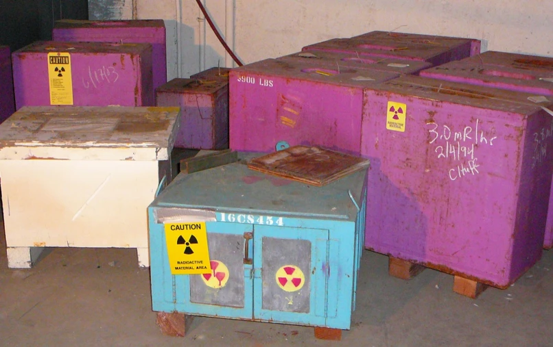 five containers sit in an old building with graffiti on them