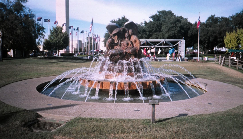 a fountain near a field with many people