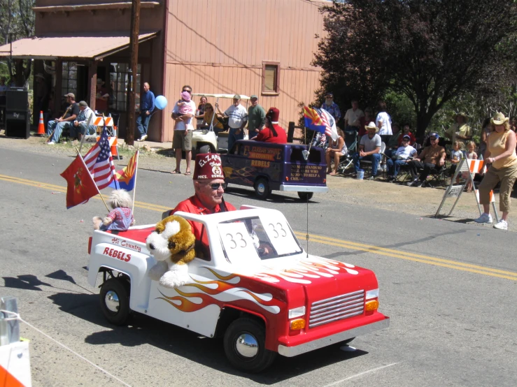 man riding on the back of a truck with a flag, flag and fire engine