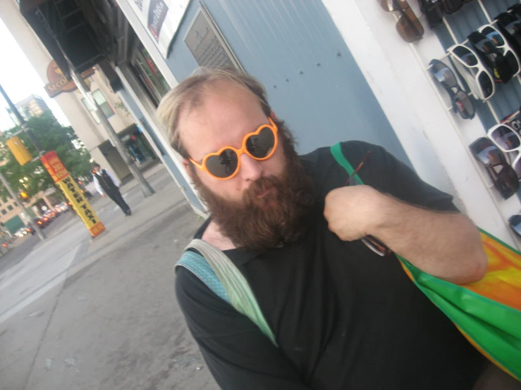 a person on a sidewalk wearing sunglasses and holding up their hand