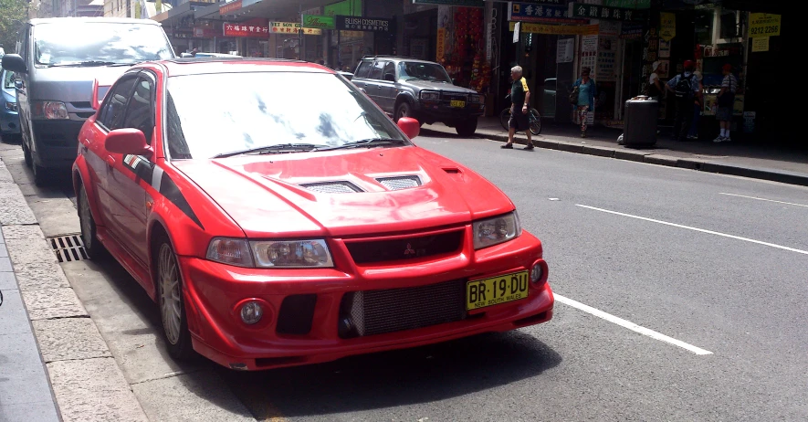 a red colored car parked on a city street