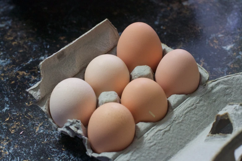an egg carton with five eggs inside on a countertop