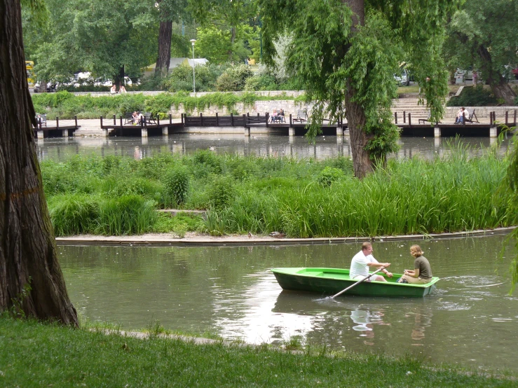 two men in a small green boat with a rope