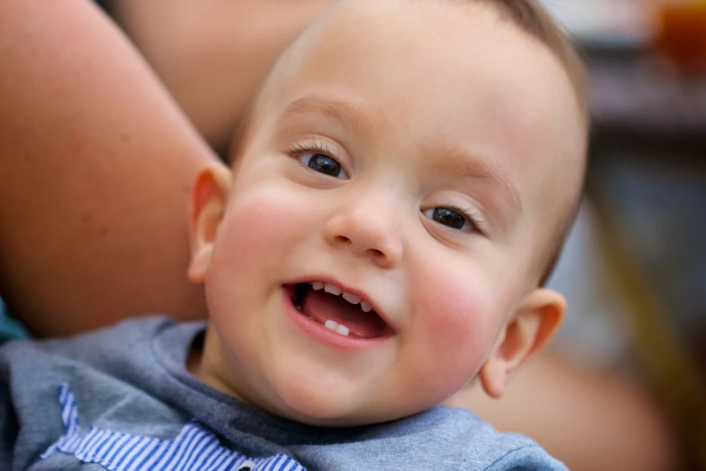 the baby smiles while being held up to his ear