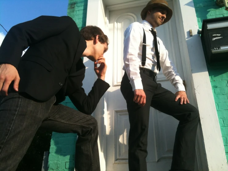 two men in suits standing on steps talking on a cellphone