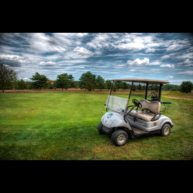 a golf cart parked on the grass in front of a field