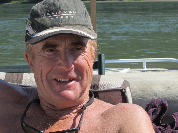 an older man sits on a boat with water in the background