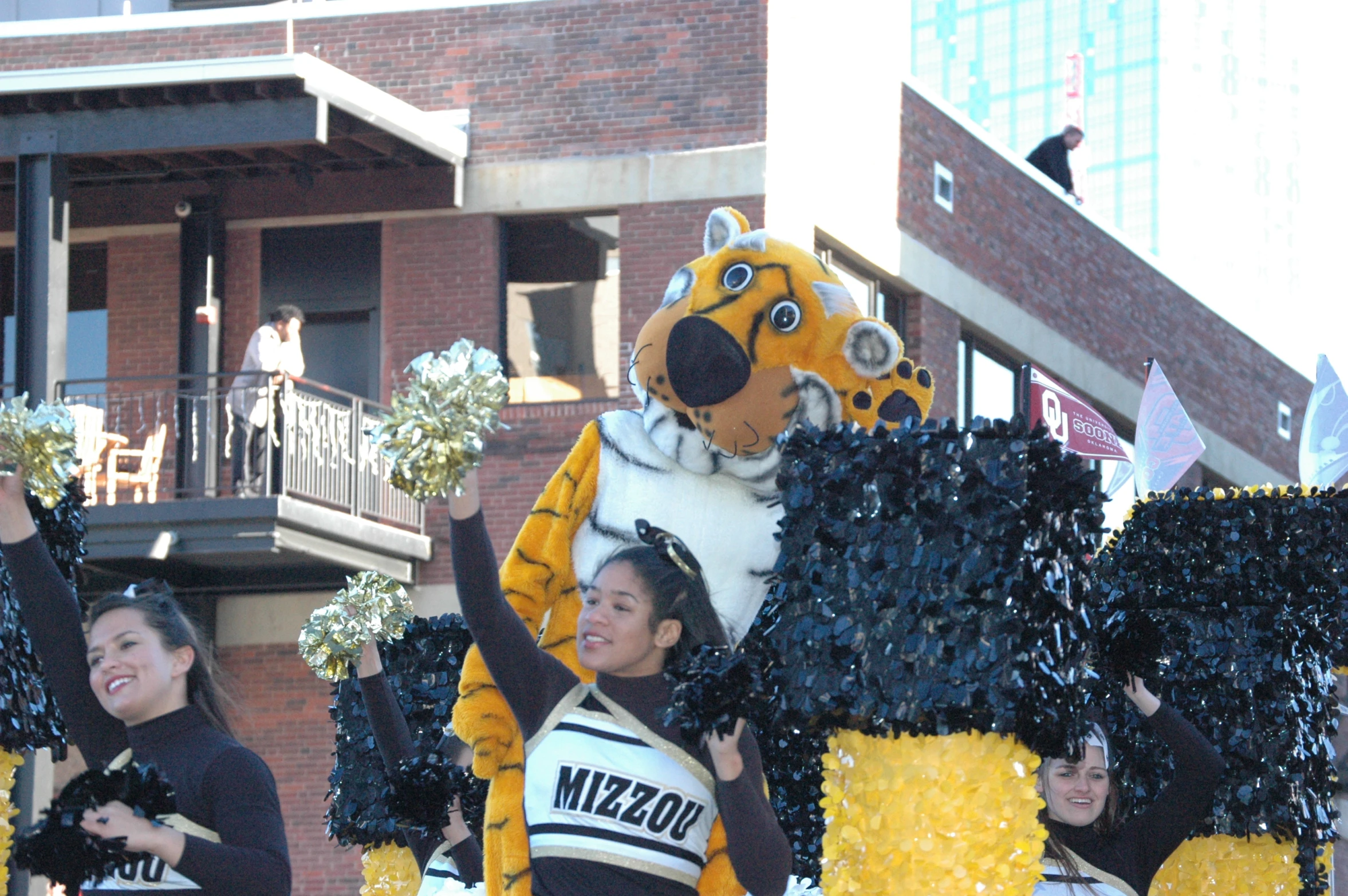 a group of cheerleaders on the street standing in front of a large tiger