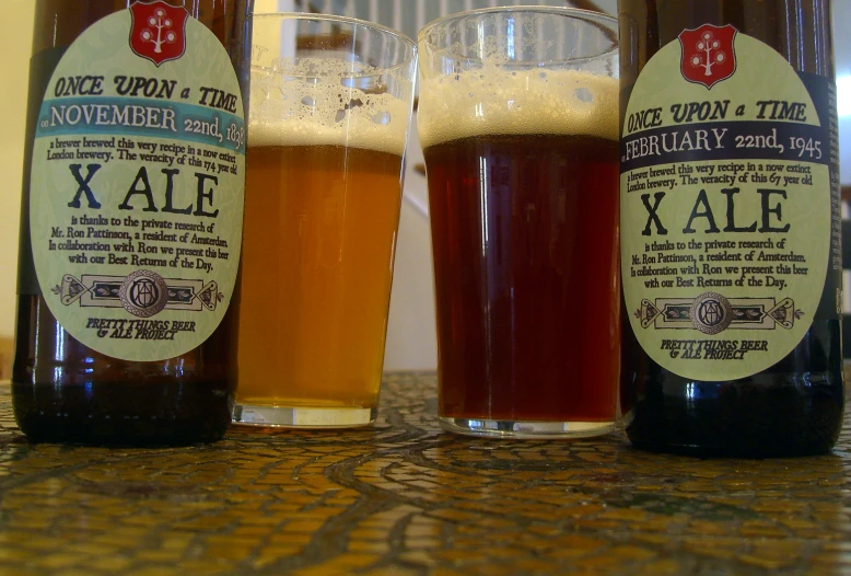 three glasses and two bottles with liquid sitting on a counter