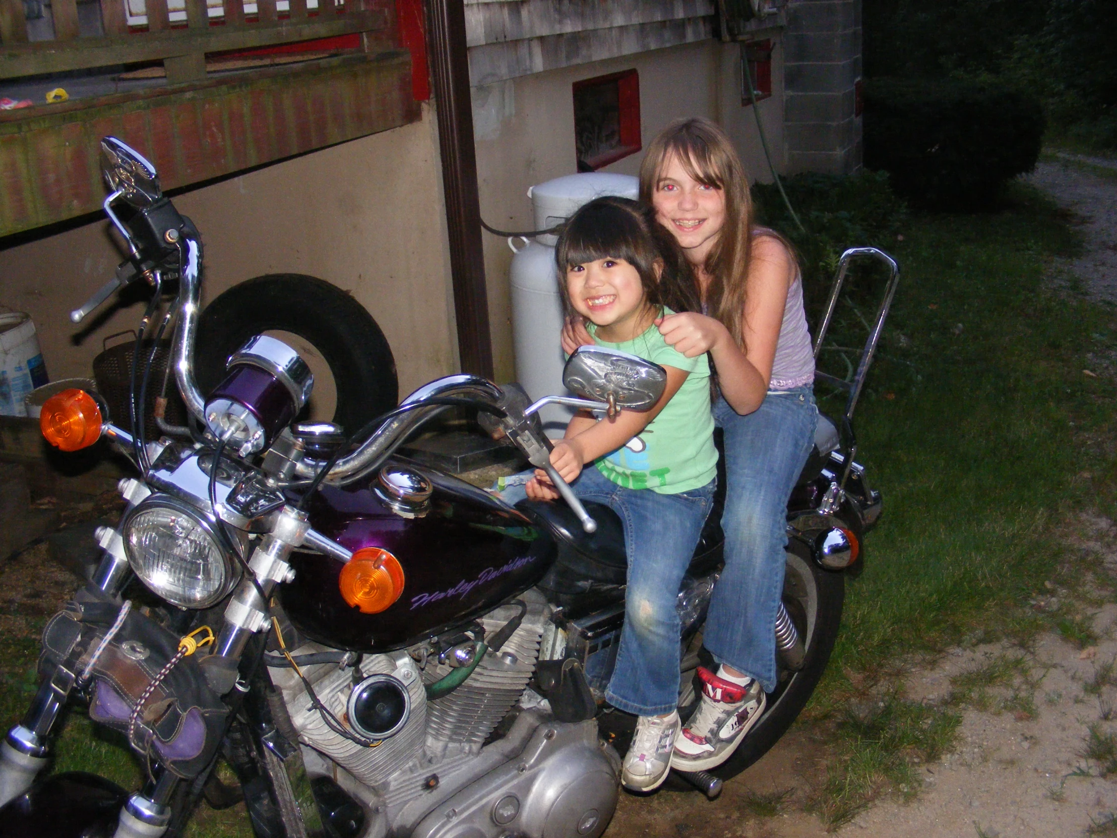 a  and girl pose on the back of a motorcycle