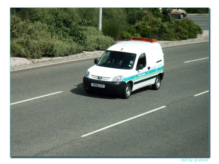 a van drives down the road near a bush