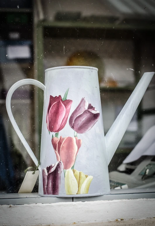 there is a tea pot with tulips painted on the side
