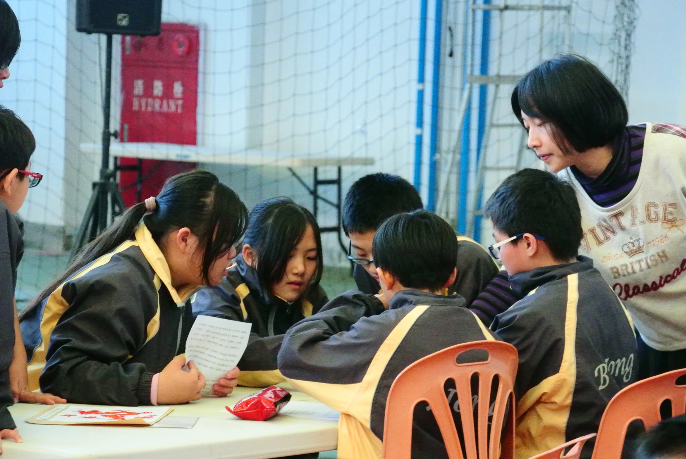 an asian student teacher helps her students to work on their work