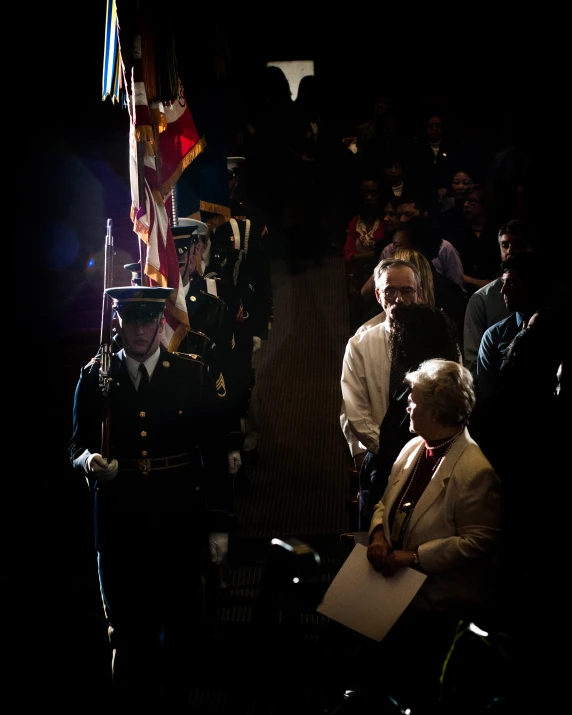 some people wearing military clothing are standing and sitting in a crowd