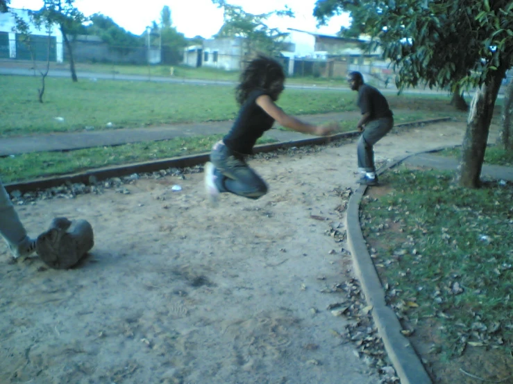 two people dancing in the dirt outside at a park